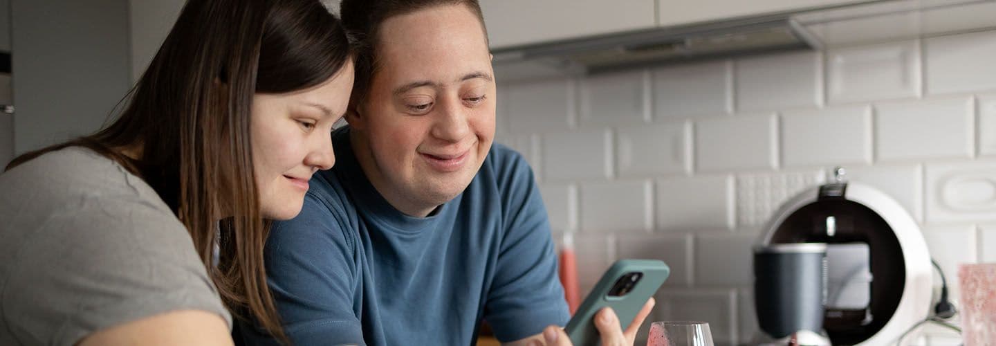 a young couple with down syndrome hang out in the kitchen