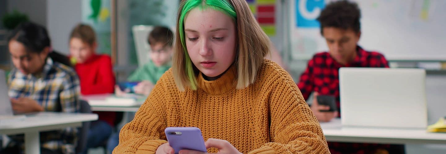 a young woman looks at her phone in class