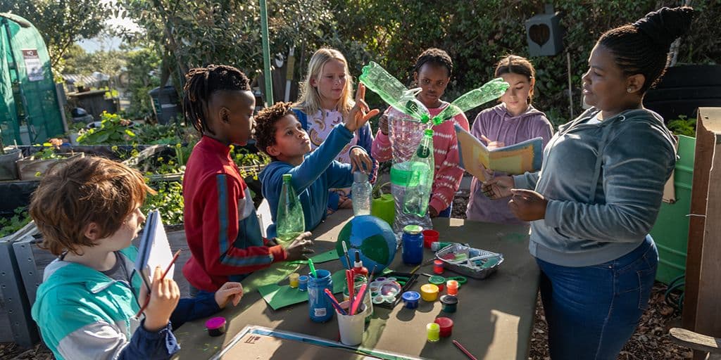 Group of school children making environmental art with their teacher
