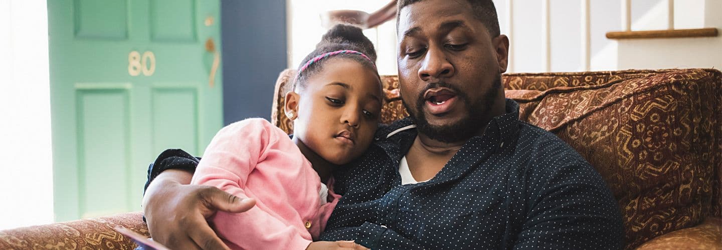 a father reads to his daughter