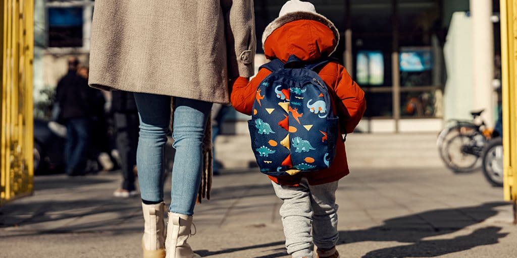 A mother entering the kindergarten yard with her son