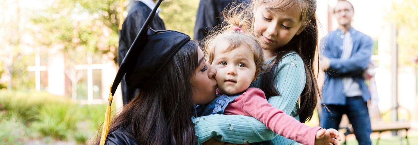 Young adult graduating mother kisses daughter