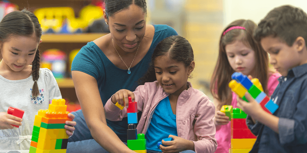 A woman helps several young children in a child care setting