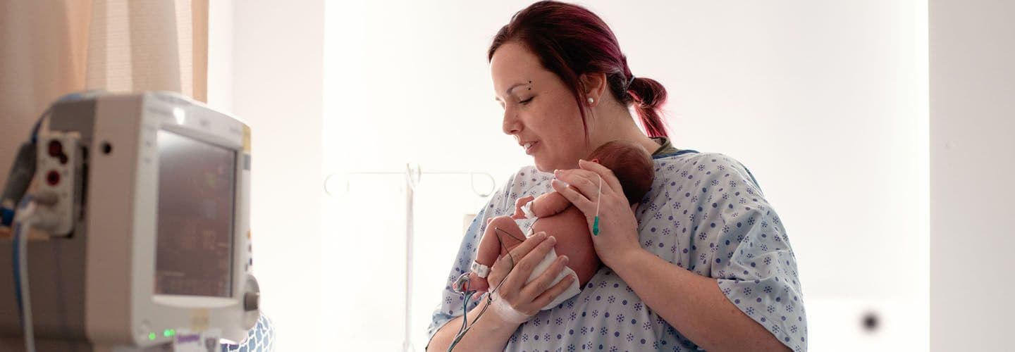 a mother holds her premature baby at the hospital