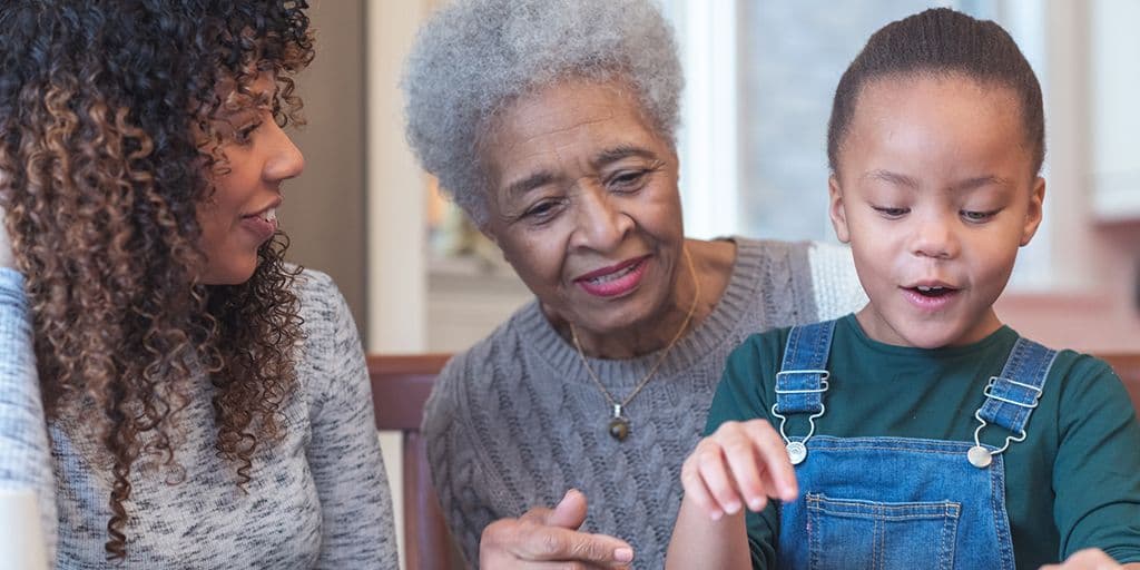 a young girl colors with her mother and grandmother