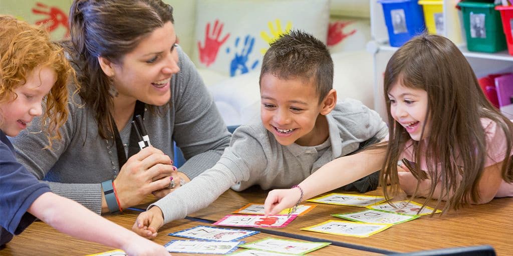 a teacher helps young students with a project