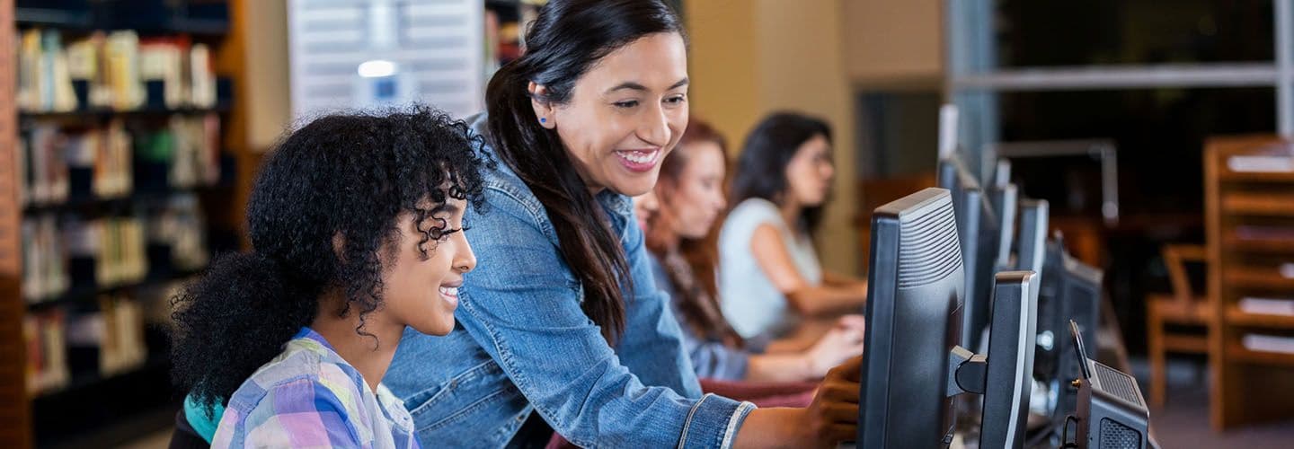 a woman helps a student on the computer