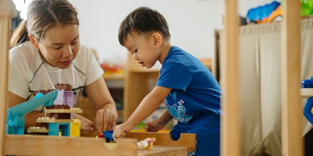 a young boy and his mom play with blocks