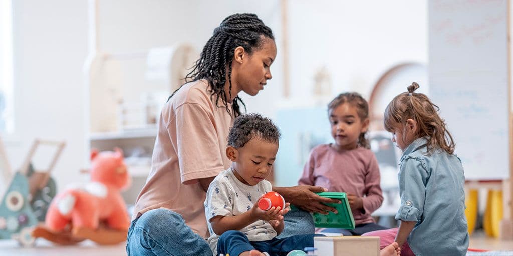 a teacher supervises young children playing together