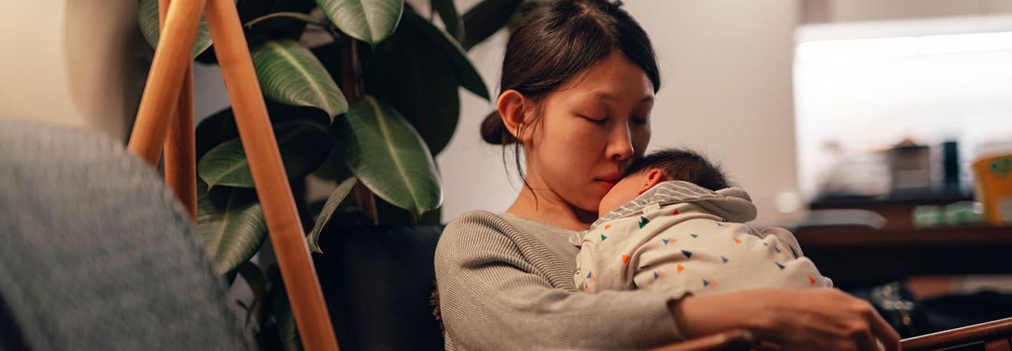 a young mother holds her baby at home