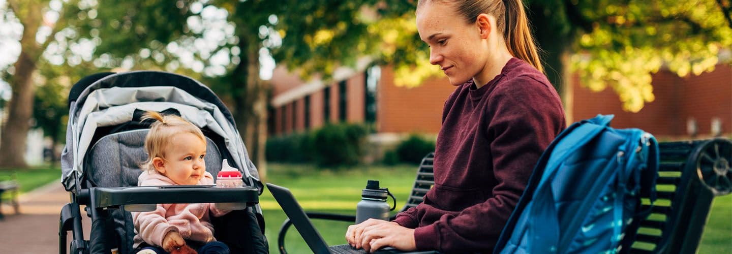 a young mother works on her laptop at school