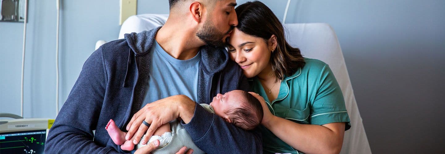 a new father and mother hold their baby
