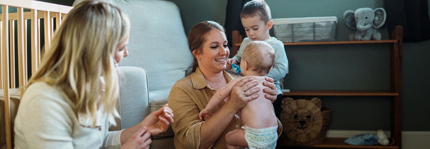 a nurse helps a mother with a young baby