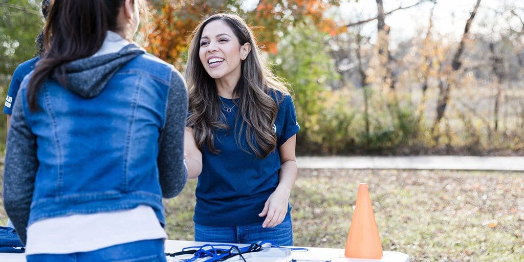 a volunteer greets a young woman