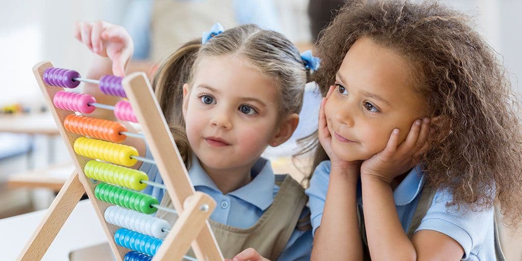 two young girls play with an abacus